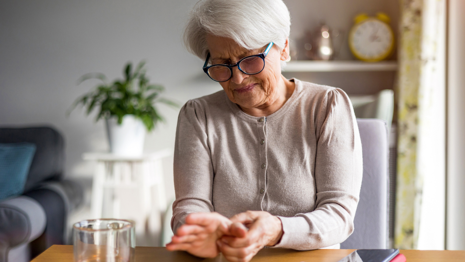 Older woman experiencing joint discomfort while sitting quietly at her table
