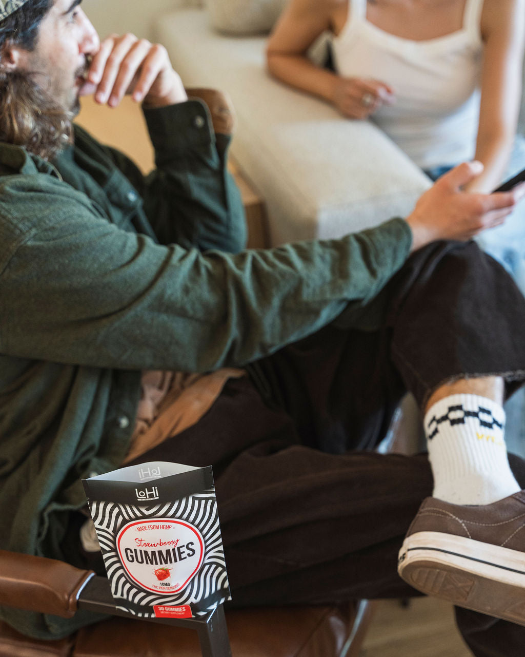 A man and a woman sitting and talking while enjoying THC gummies for stress.