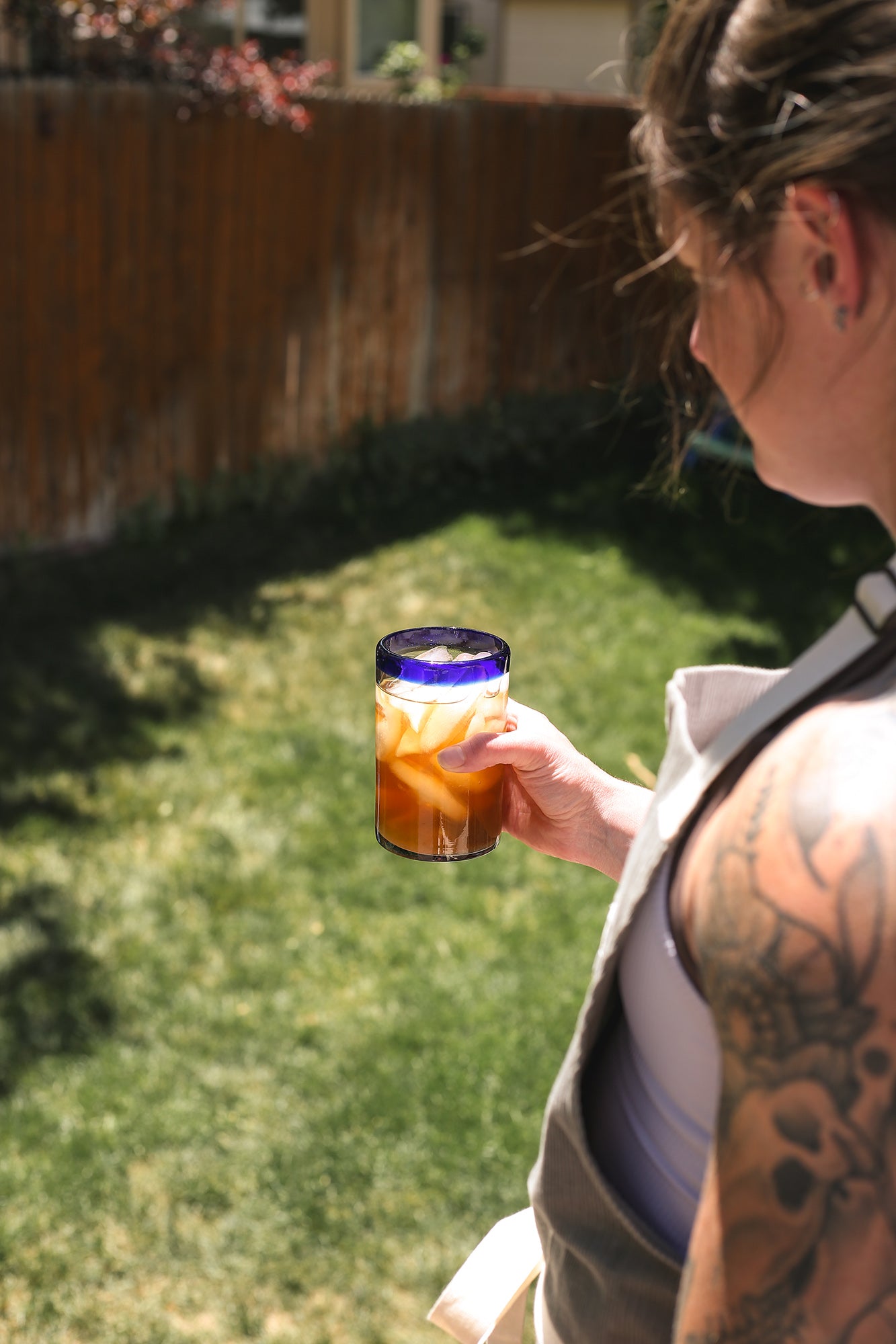 A woman holding a glass of THC-infused peach ice tea.