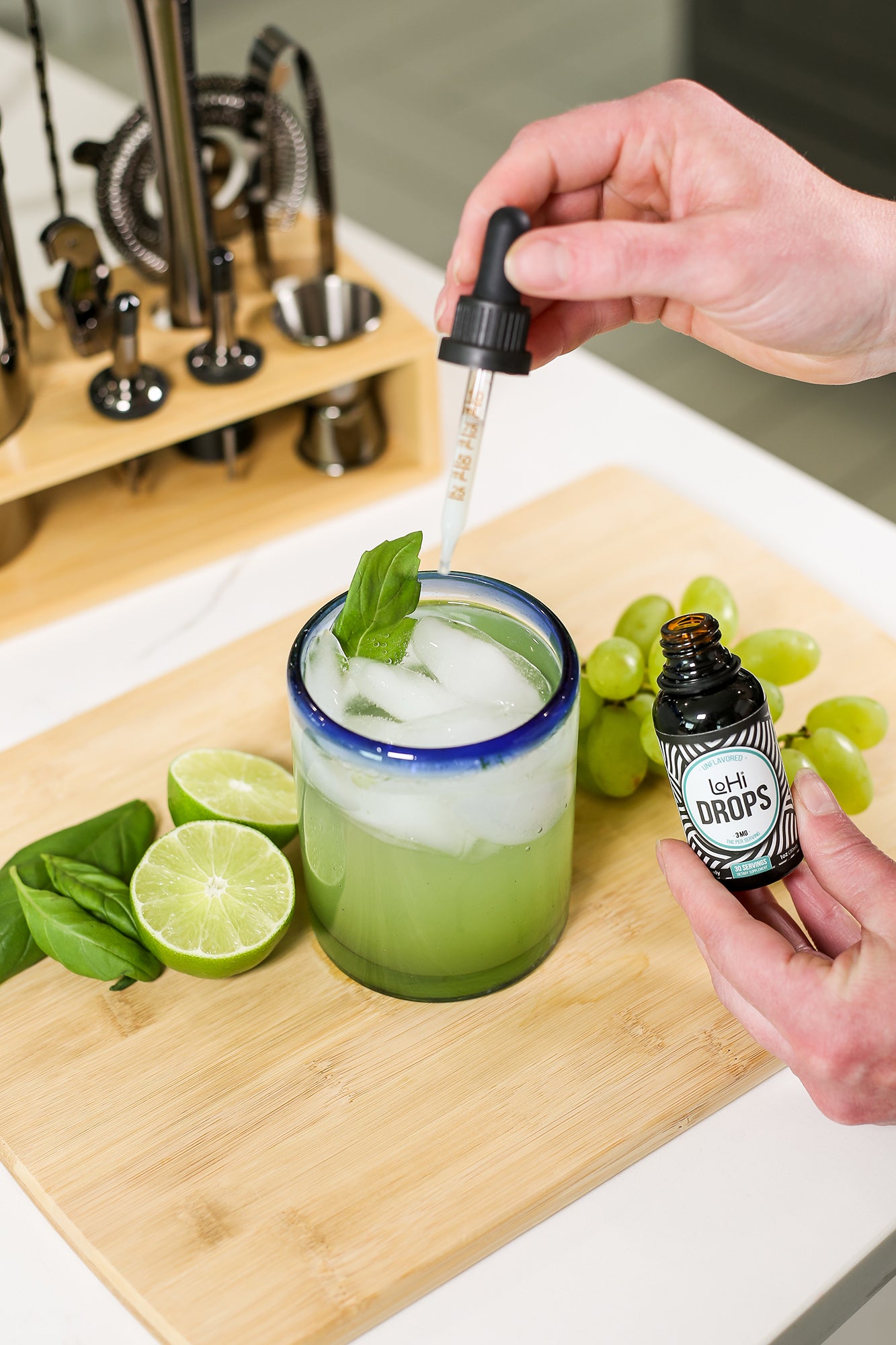 A woman's hands adding LoHi THC drops to a gin basil smash mocktail