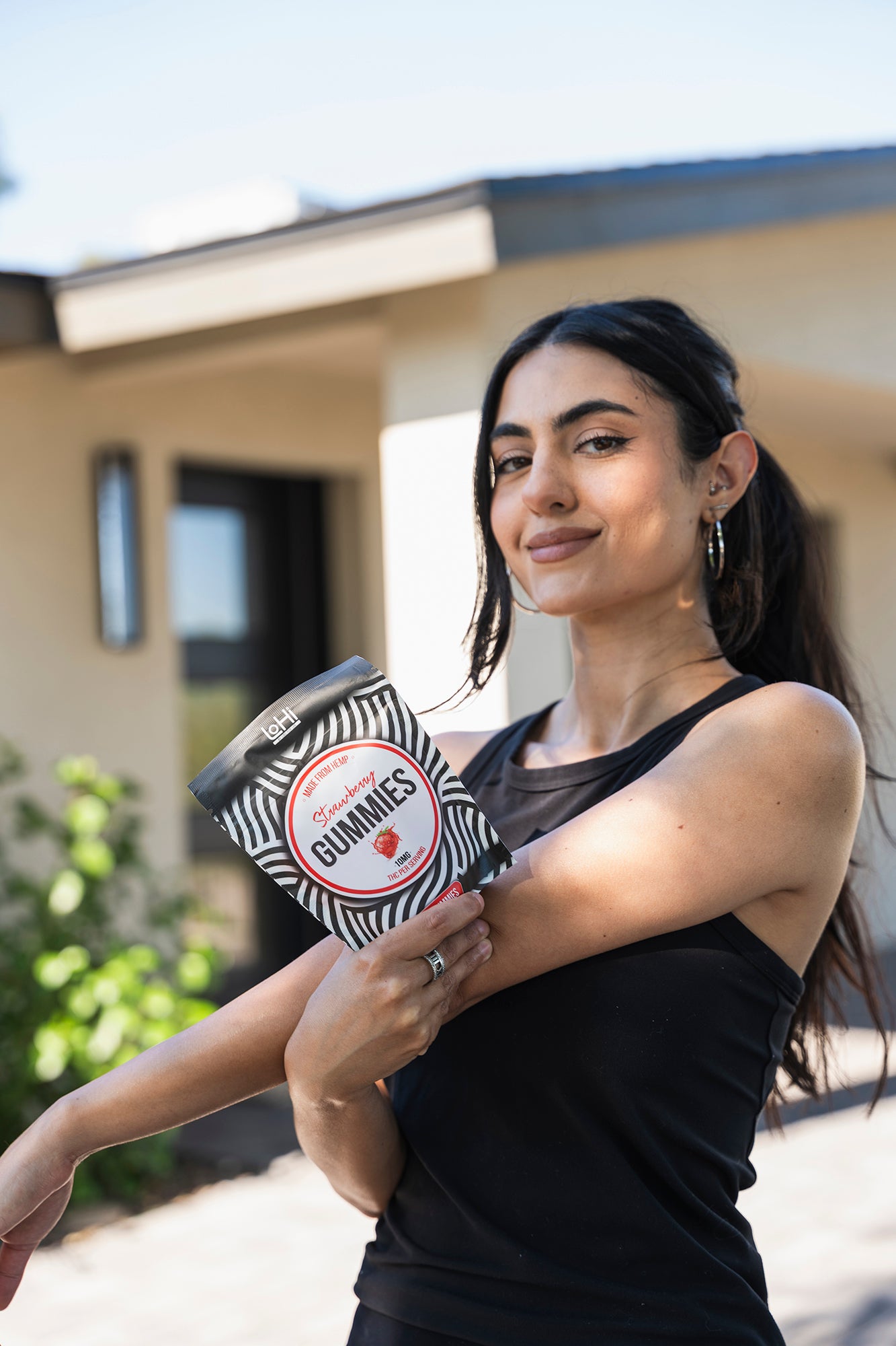 woman in black tank top holding THC gummies